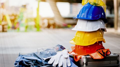 Arbeitnehmerschutzbehörde Arbeitsschutzkleidung und Bauhelme vor einer Baustelle