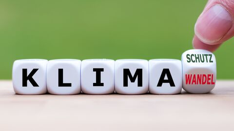 Klimaschutz  Aneinandergereihte Würfel mit den Buchstaben "KLIMA", ein Finger dreht den letzten Würfel um, sodass man die Wörter "Schutz" und "Wandel" lesen kann