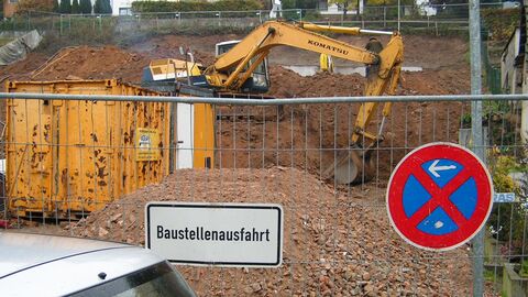 Eine Baustelle mit Bagger, Baucontainer, und Bauschutt 