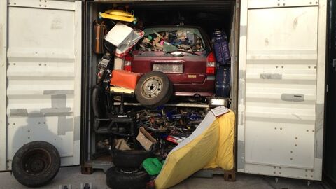 Verschiedener Abfall, wie zum Beispiel ein Auto, Matratze oder Reifen, sind in einem Container gelagert