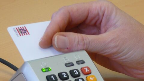 Eine Hand, die eine Karte in ein silbernes Signaturgerät steckt