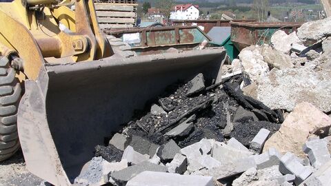 Straßenaufbruchmaterialien werden von einem Bagger geräumt 