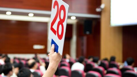 Eine Hand hält ein Schild mit einer roten 28 hoch