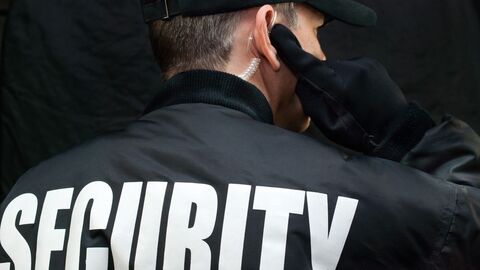 Mann mit schwarzer Jacke mit Rückenaufschrift Security