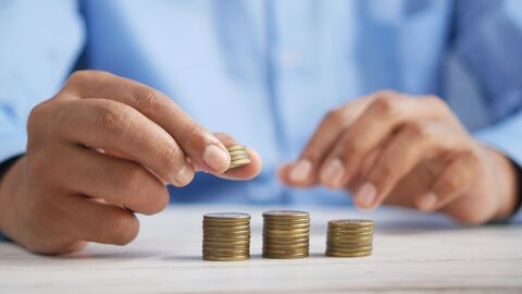 Finanzunternehmen Ein Mann in blauem Hemd stapelt Euro-Münzen