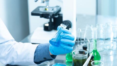 Hand hält Erlenmeyerkolben mit blauer Flüssigkeit Hand hält Erlenmeyerkolben mit blauer Flüssigkeit im Labor