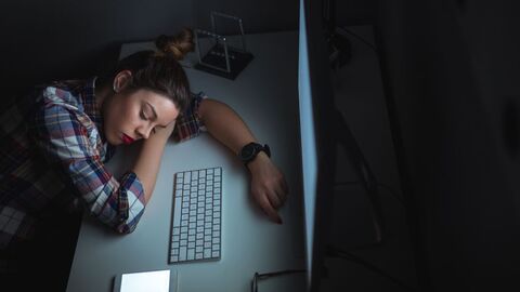 Das Arbeitszeitgesetz soll Arbeitsüberlastung vorbeugen junge Frau ist erschöpft am Bildschirmarbeitsplatz eingeschlafen
