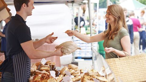 Reisegewerbe An einem Marktstand bezahlt eine Frau ihren Einkauf