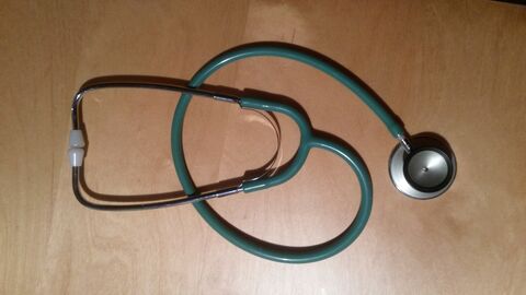 Ein schwarzes Stethoskop liegt auf braunem Untergrund