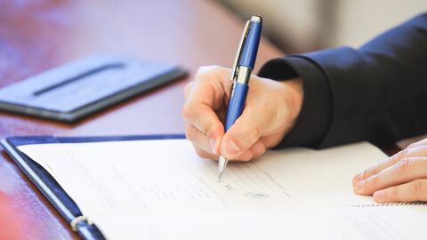 Schreibende Hand Eine Hand schreibt mit einem Kugelschreiber auf ein Blatt Papier