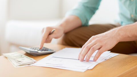 Wohngeld Person tippt an einem Tisch in einen Taschenrechner