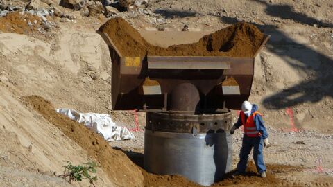 Bodensanierung eines Mineralölschadens Mann in einer Baugrube mit schwerem Schaufelgerät daneben