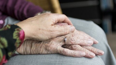 Hand auf Hand Eine junge Hand liegt auf einer alten Hand