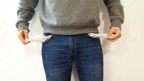 Mensch der in seine leeren Hosentaschen greift