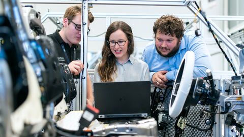 Produktion von Kraftfahrzeugen (Symbolbild) Drei Ingenieure befinden sich in einer Werkstatt und basteln an einem Auto herum.