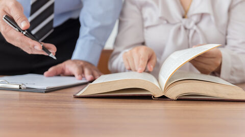 Zwei Personen sitzen an einem Tisch mit aufgeschlagenen Büchern.
