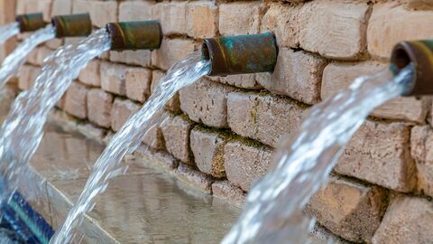 Aus Wasserrohren läuft Trinkwasser in ein Becken