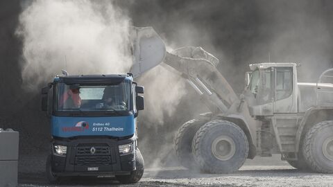 staubende Baufahrzeuge Auf dem Bild lädt ein Bagger staubendes Material auf einem LKW ab.