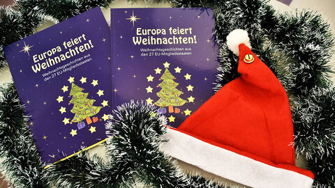 Zwei Weihnachtsbücher mit Tannengrün und Nikolausmütze auf einem Tisch
