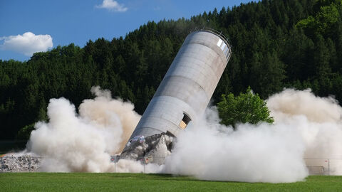Sprengung eines Gebäudes (Symbolbild) Kippender Betonturm, an dessen Fuß große Staubwolken