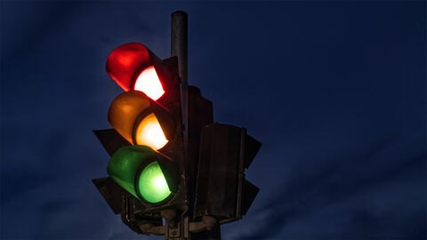 Ampel bei Nacht, es leuchten die Farben Rot, Gelb und Grün gleichzeitig
