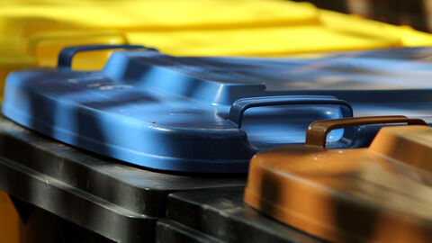 Nahaufnahme von Mülltonnendeckeln in Gelb, Blau und Braun