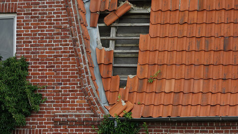 Schäden (Symbolbild) Nahaufnahme eines Hausdachs, bei dem mehrere Ziegel fehlen