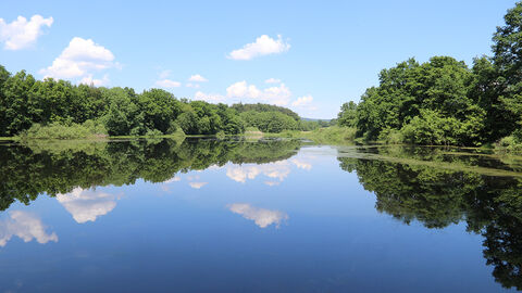 Spießweiher – Talauen von Nidder und Hillersbach bei Gedern und Burkhards (Flora-Fauna-Habitat-Gebiet 5520-302) Blick über einen See auf Wälder, im Wasser spiegeln sich einzelne Wolken