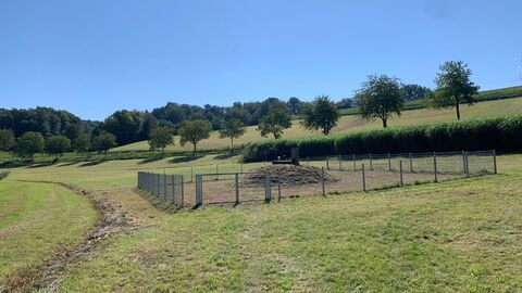 Wiese mit eingezäuntem Areal und künstlicher Erhebung darauf