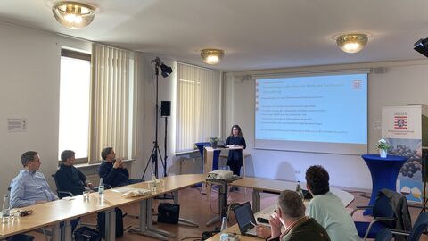 Eva Dingeldey vom Weinbau-Dezernat des RP spricht am Sachkunde-Nachmittag.  Frau spricht vor Leinwand zu Personen an Tischen im Raum