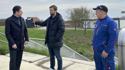 Drei männliche Personen stehen auf einer Brücke.