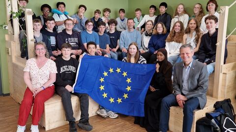 Gruppe von jungen Menschen mit Europa-Fahne in Ausstellungsraum.