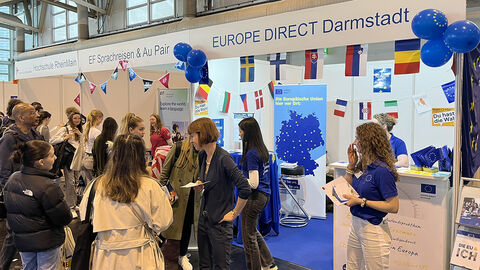 Heike Hofmann am Stand des Europe Direct Darmstadt Mehrere Personen an einem Infostand in einer Messehalle