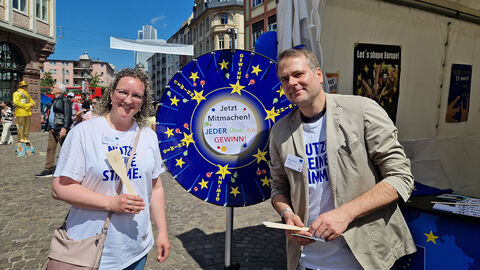 Europe Direct Darmstadt beim Europafest in Frankfurt Zwei Personen, in der Mitte ein Glücksrad