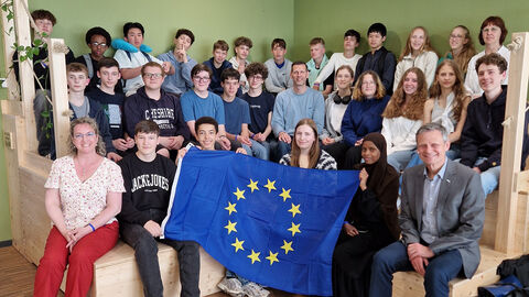 Gruppenbild der Teilnehmerinnen und Teilnehmer Schulklassen mit Begleitpersonen und einer Europaflagge