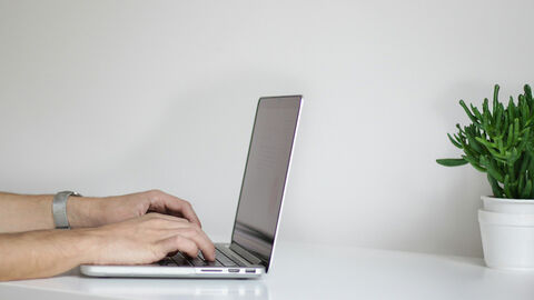 Online-Dienste (Symbolbild) Person tippt mit beiden Händen auf der Tastatur eines Laptops, Seitenansicht