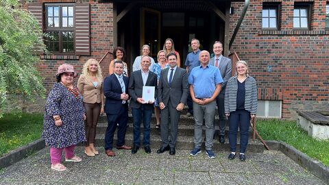 Menschengruppe steht vor Gebäude.