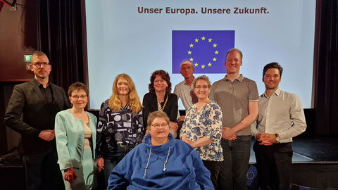 Gruppenbild der Beteiligten Mehrere Personen vor einer Kinoleinwand, auf der steht „Unser Europa. Unsere Zukunft.“