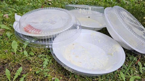 Weggeworfenes Einweg-Kunststoff-Geschirr auf einer Wiese