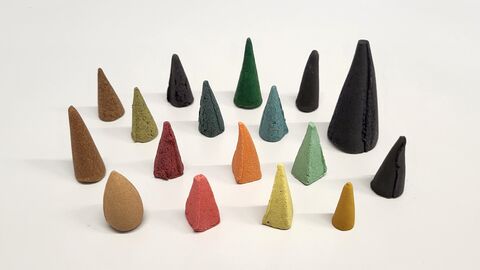Auswahl der überprüften Räucherkerzen Mehrere kleine bunte Kegel leicht unterschiedlicher Größe stehen auf einer weißen Fläche