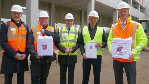 Fünf Männer mit weißem Helm und bunten Warnwesten auf Baustelle