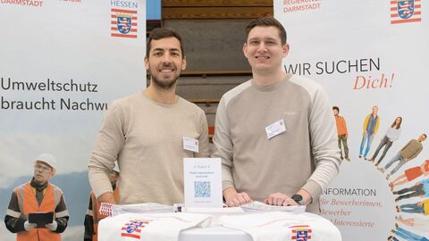 RP Darmstadt wirbt auf Ausbildungsmessen Zwei Männer stehen hinter einem Stehtisch. Hinter ihnen sind zwei Banner aufgestellt.