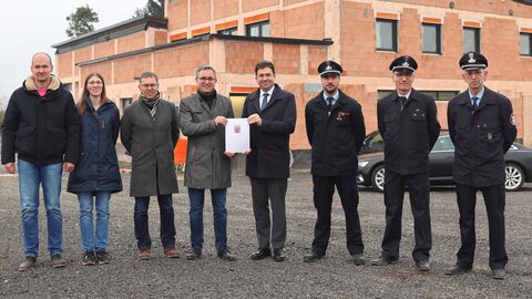Acht Personen vor Haus im Rohbau