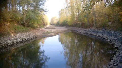 Gewässer in Flußbett, an der Seite jeweils Uferböschung