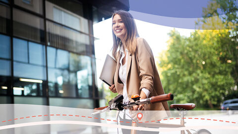 Einstieg ins Arbeitsleben (Symbolbild) Junge Frau schiebt mit der einen Hand ein Fahrrad und hat einen Laptop in der anderen