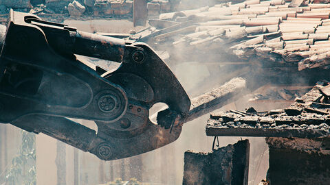 Ein Greifer entnimmt eine Metallstrebe aus einem Abbruchgebäude