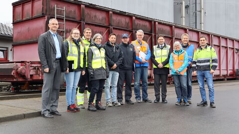 Elfköpfige Gruppe von Personen vor großem, roten Container