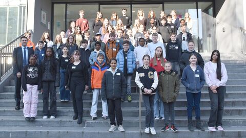 Viele Kinder und Jugendliche stehen auf einer großen Treppe vor einem Gebäude.