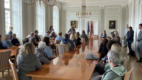 Menschen sitzen an Konferenztisch in Saal