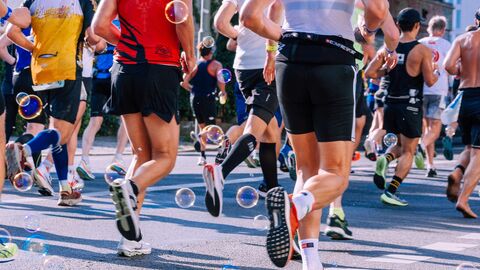 Mehrere Menschen joggen auf einer Straße entlang. Sie sind alle von hinten zu sehen.